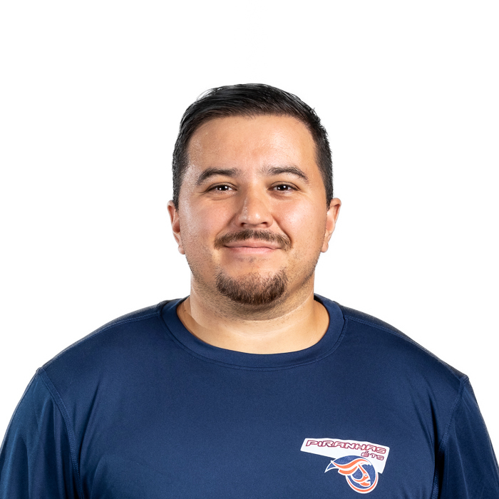 Portrait d'un homme souriant, portant un t-shirt bleu avec le logo "Piranhas", mettant en avant une ambiance amicale et professionnelle.