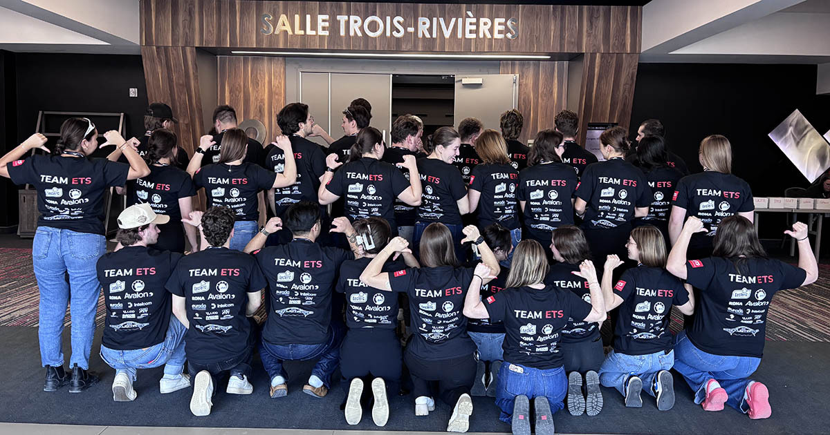 A group of students wearing matching Team ETS shirts celebrates unity and teamwork at a university event.