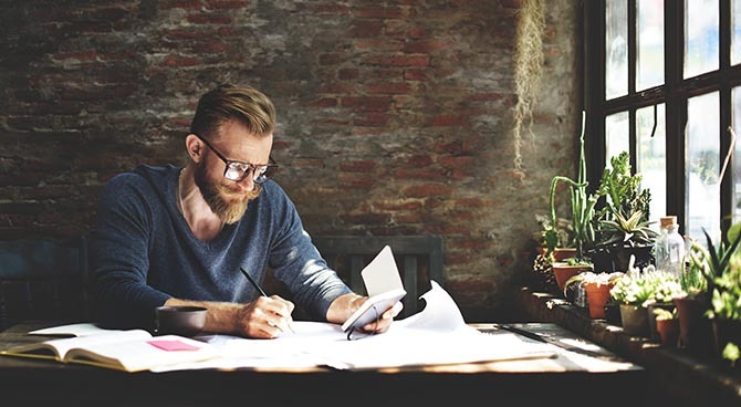 Etudiant concentré travaillant sur son projet dans un espace lumineux et rustique.