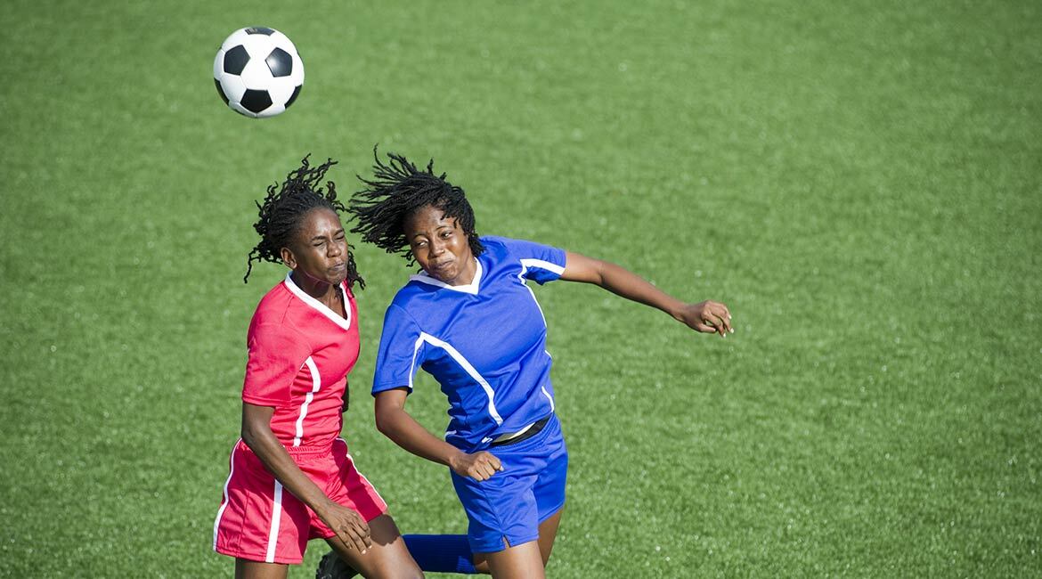 Two players competing in soccer on a vibrant green field.