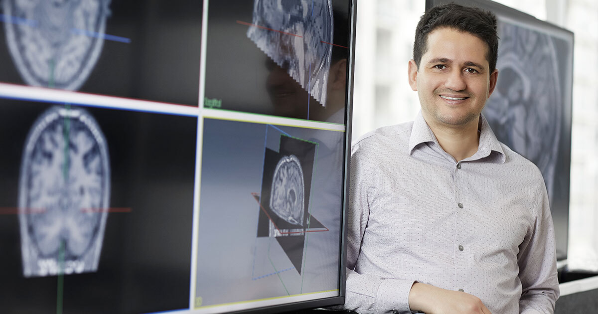 A researcher stands beside advanced brain imaging displays, showcasing innovative technology in neuroscience.