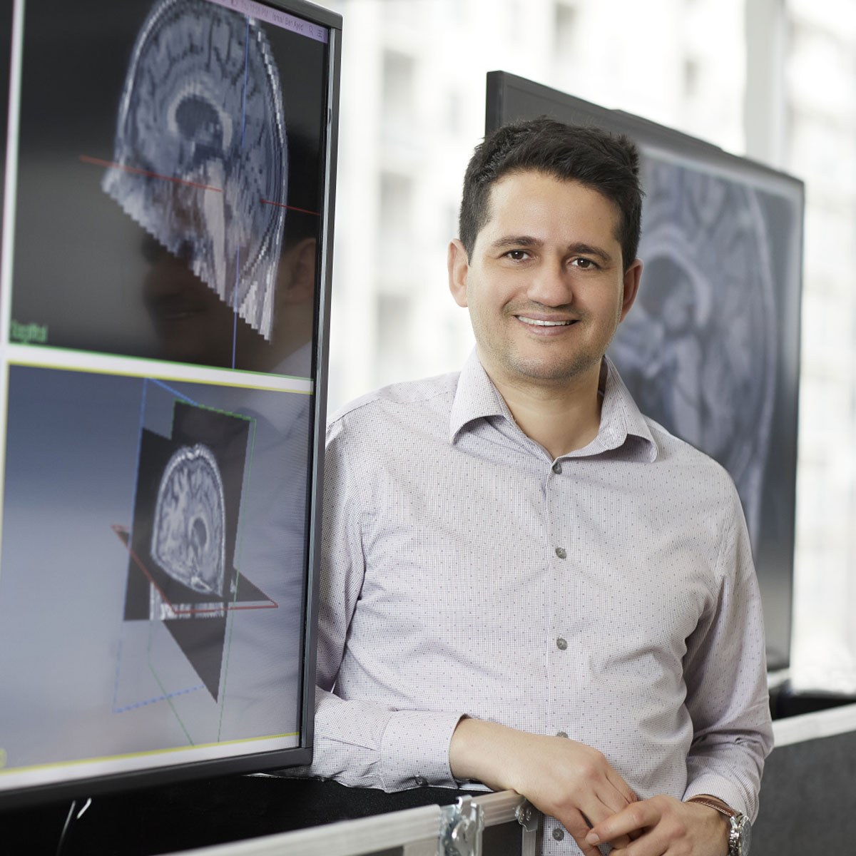 Le professeur-chercheur Ismail Ben Ayed aux côtés d'images cérébrales sur des écrans, illustrant des avancées en technologie médicale.