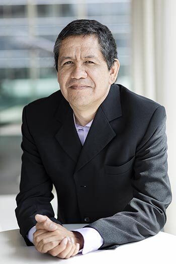 University faculty member in a suit, smiling confidently with an academic backdrop.