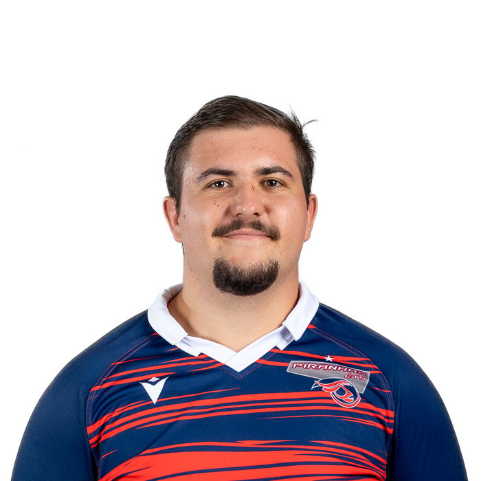 Jeune homme souriant portant un maillot de rugby aux couleurs vives, affichant fierté et détermination.