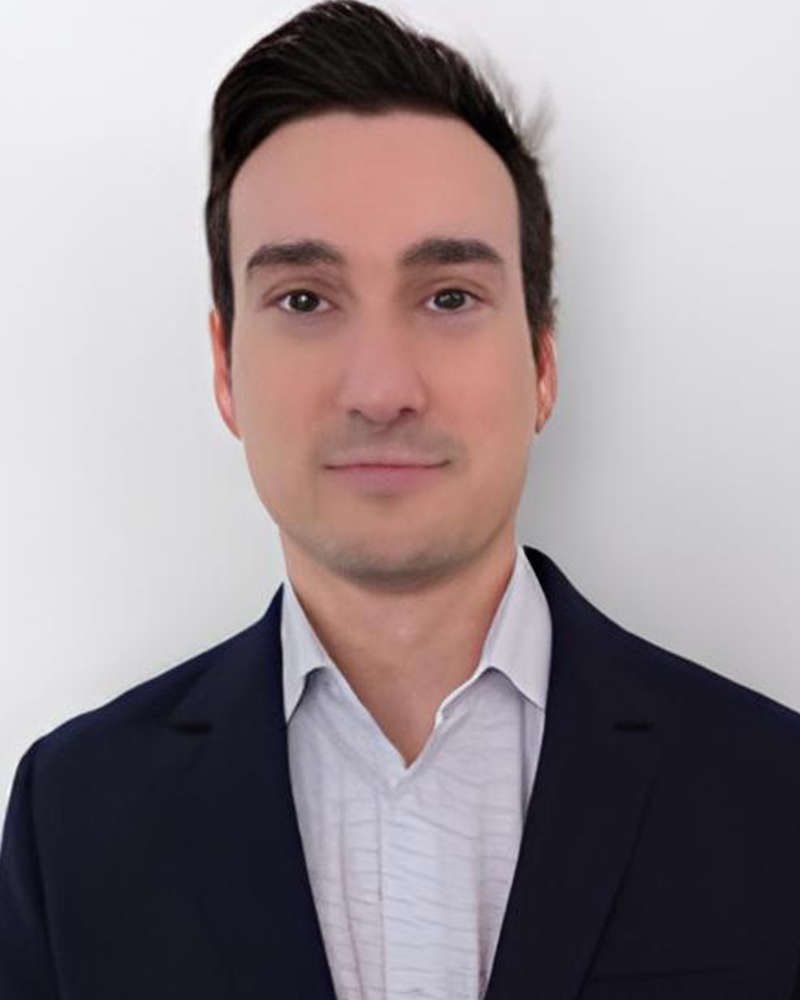 Jeune professionnel en tenue d'affaires, souriant et confiant, devant un fond neutre. Il incarne l'esprit académique et dynamique de l'université.