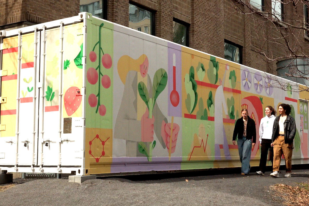 Trois personnes marchent devant un conteneur décoré de motifs colorés sur la nature et la science, symbolisant l'innovation et l'éducation.