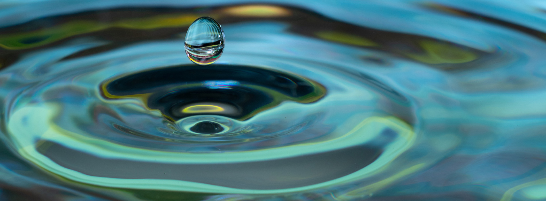 Goutte d'eau suspendue, jeu de lumière et couleurs fluides.