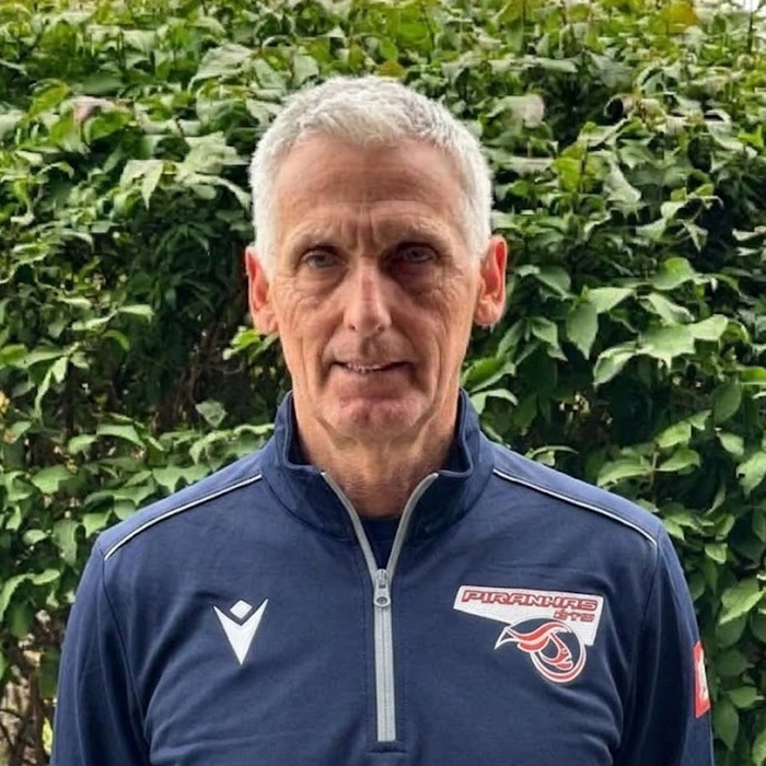 Homme mature en veste sportive, observant attentivement, ambiance de stade.