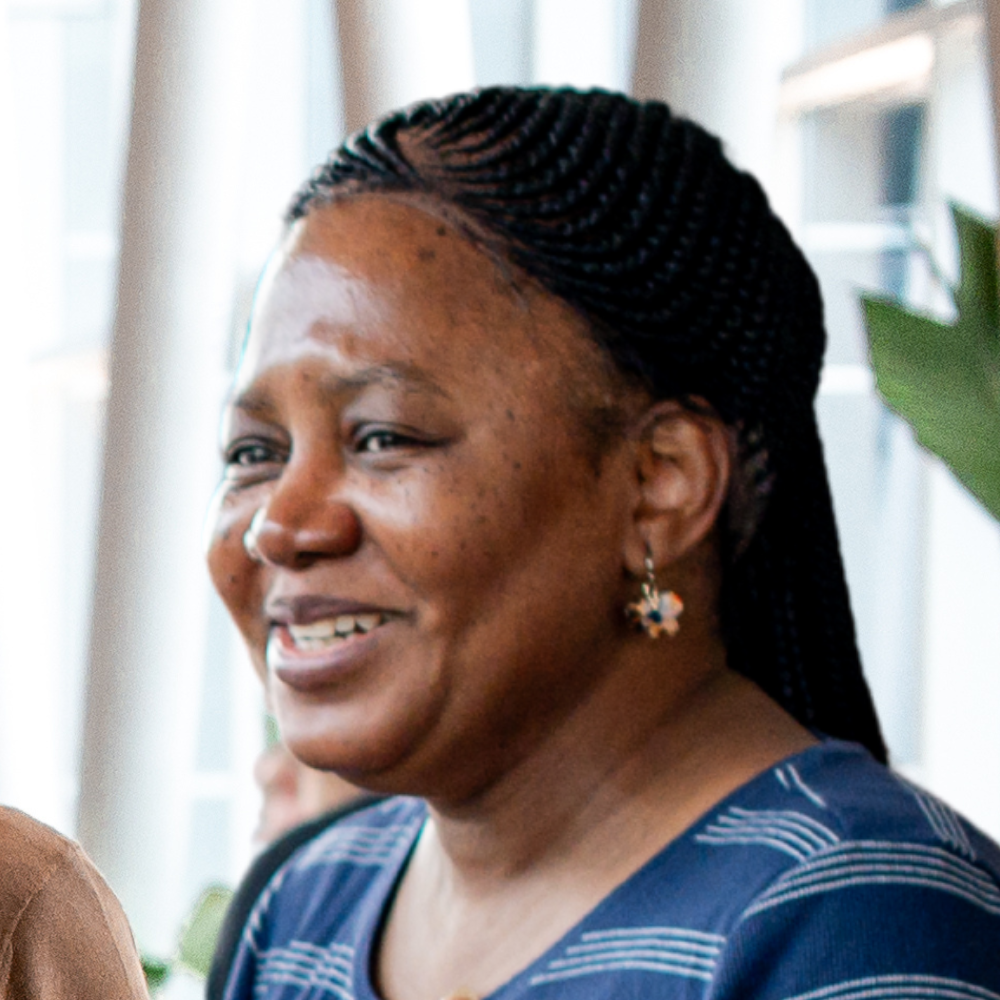 Two individuals engaging in a friendly conversation, showcasing smiles and expressions of warmth in a professional setting.