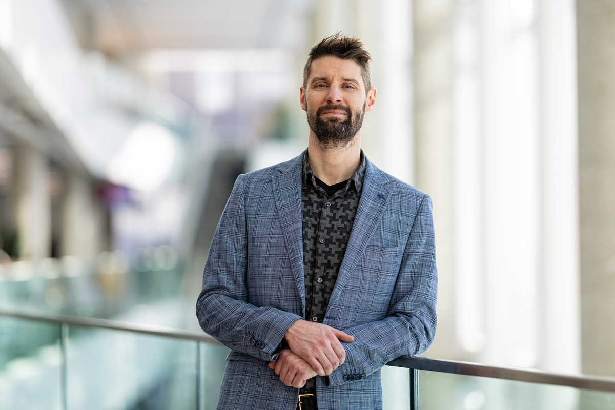 A professional male with a stylish look, standing confidently in a modern educational environment, showcasing innovation and expertise.