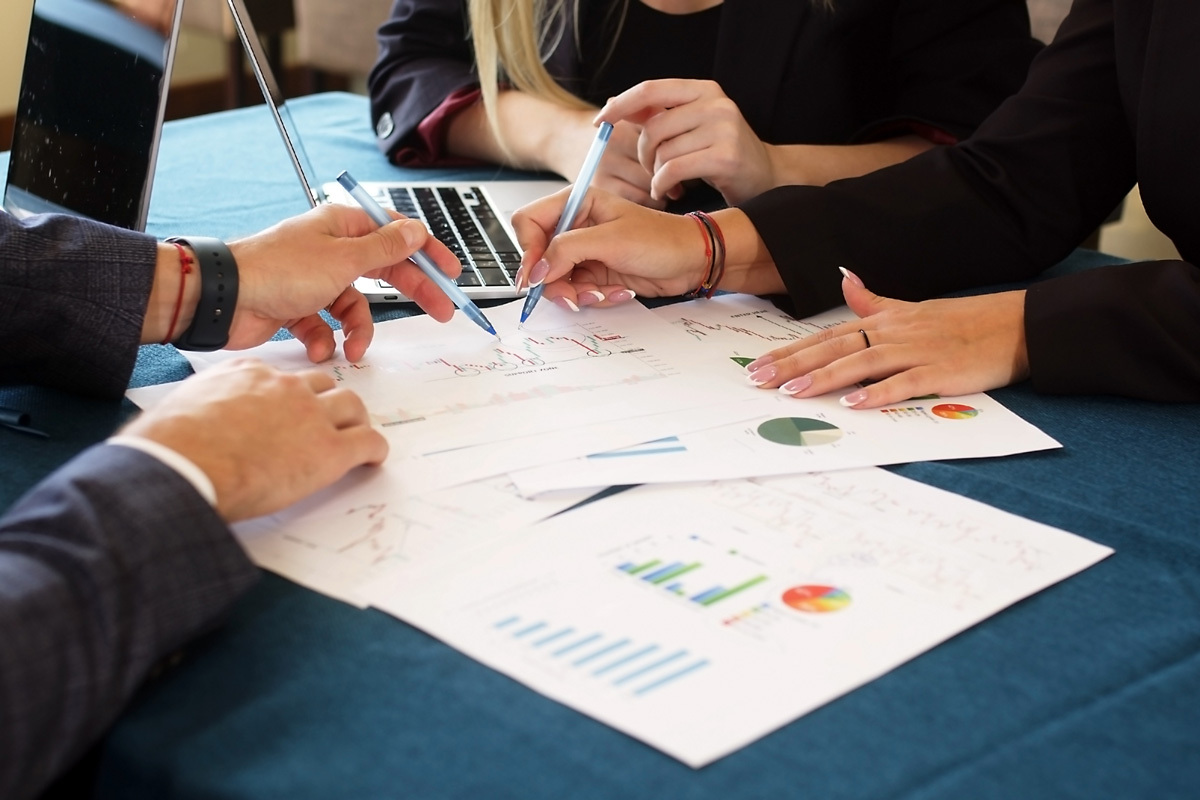 Collaboration in progress, with hands analyzing data on charts and graphs, supporting effective decision-making in technology.