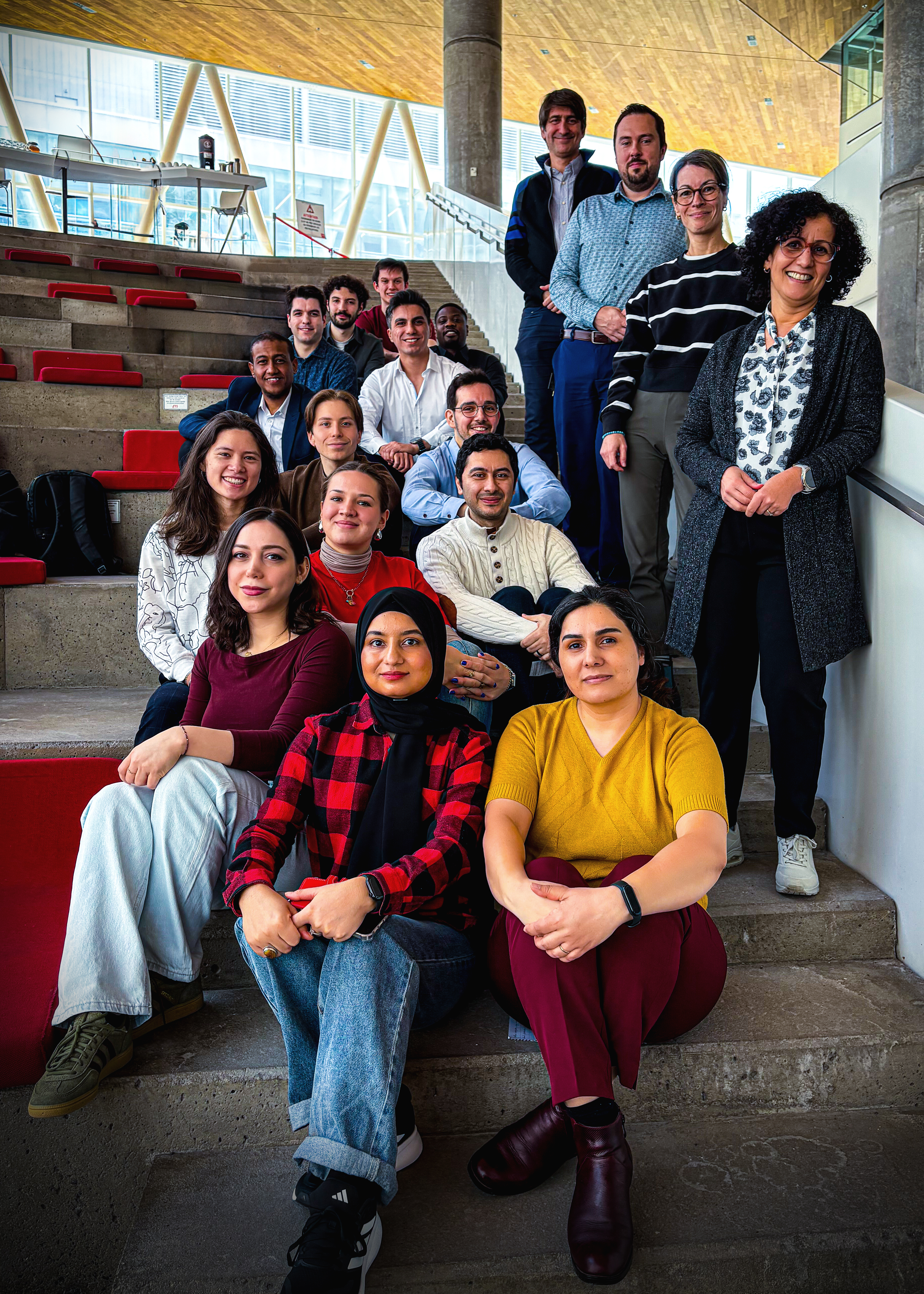 Groupe d'étudiants et d'enseignants réunis dans un cadre moderne, affichant enthousiasme et camaraderie au sein de l'université.