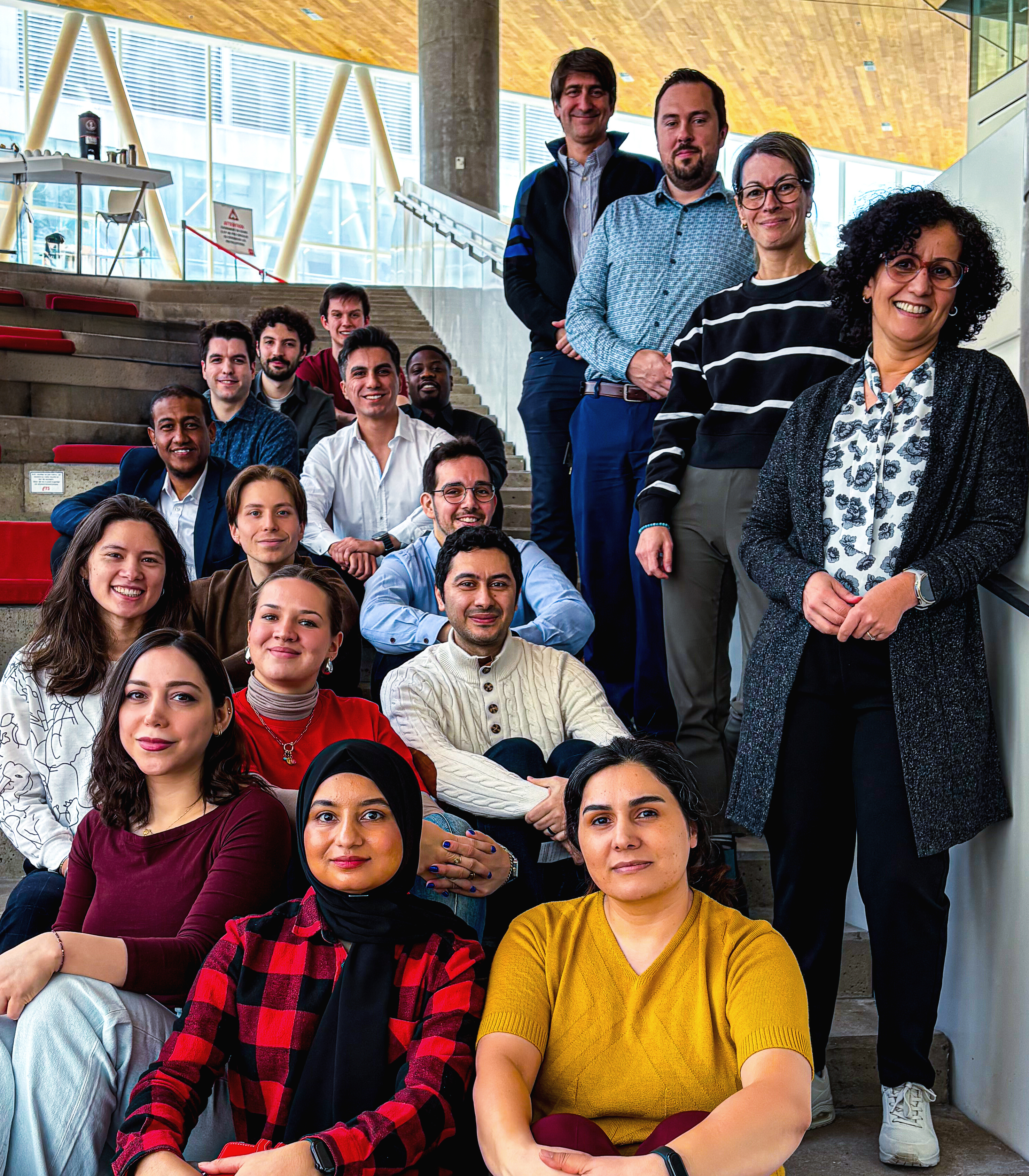 A diverse group of students and professors poses together at a modern university setting, showcasing collaboration and community spirit.
