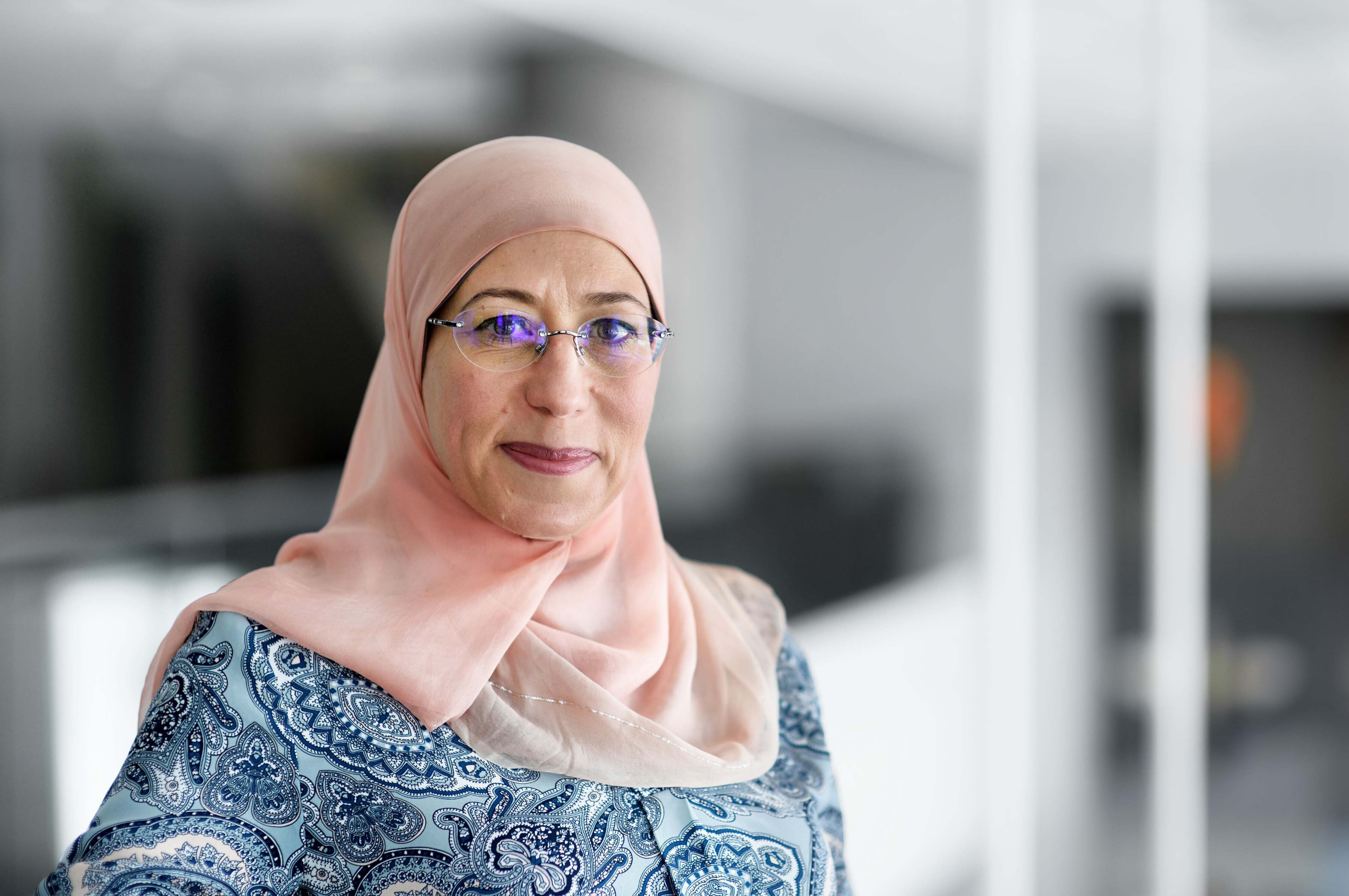 Professeure en technologie avec hijab dans un milieu universitaire.