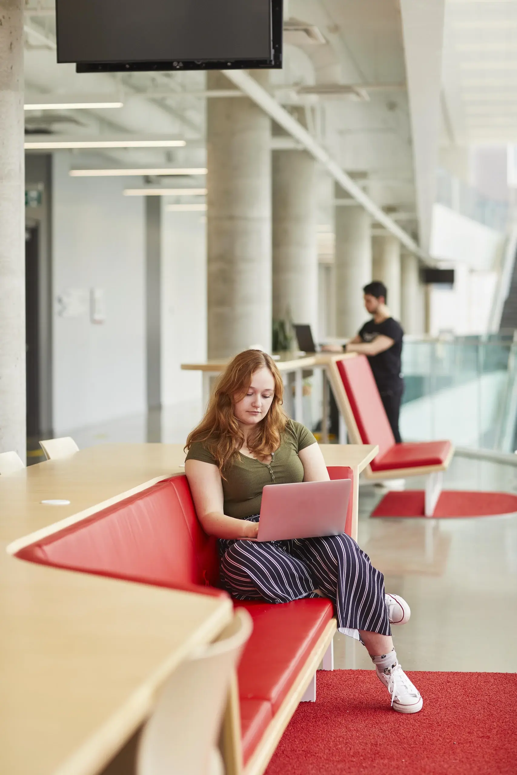 Student sitting on a red bench at the Maison des étudiants.