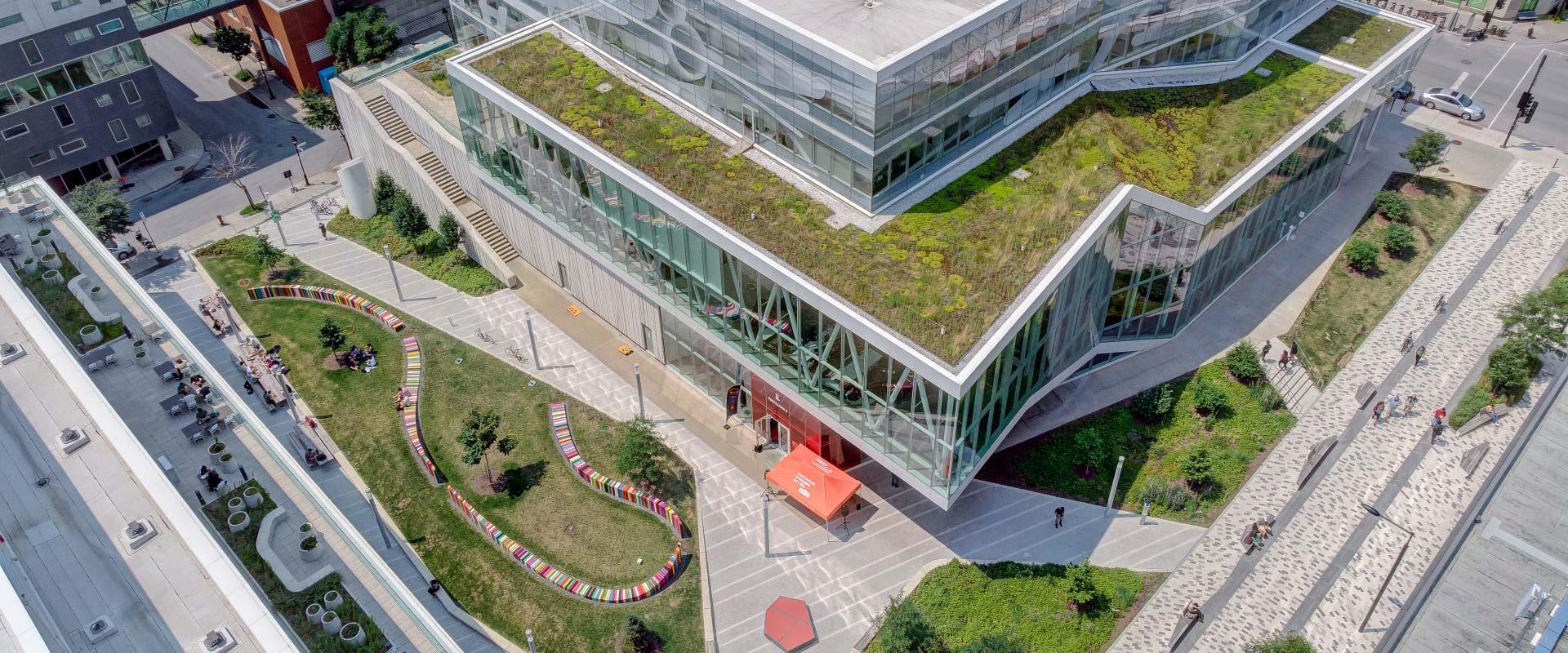 Un bâtiment moderne avec une toiture végétale, entouré d'espaces verts et de zones de détente pour les étudiants.