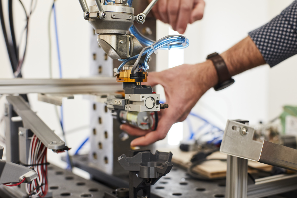 A technician adjusts a robotic arm component in a high-tech research environment, showcasing advanced engineering and automation.