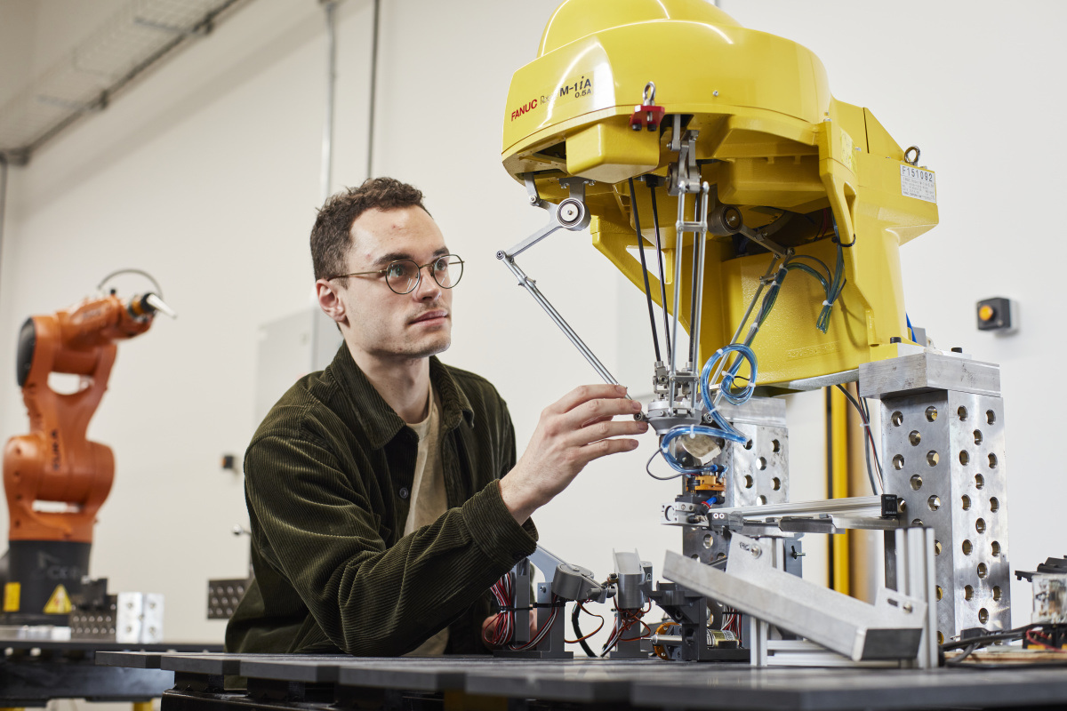 Un étudiant en ingénierie travaille avec un robot dans un laboratoire de technologie avancée, explorant les innovations en robotique.