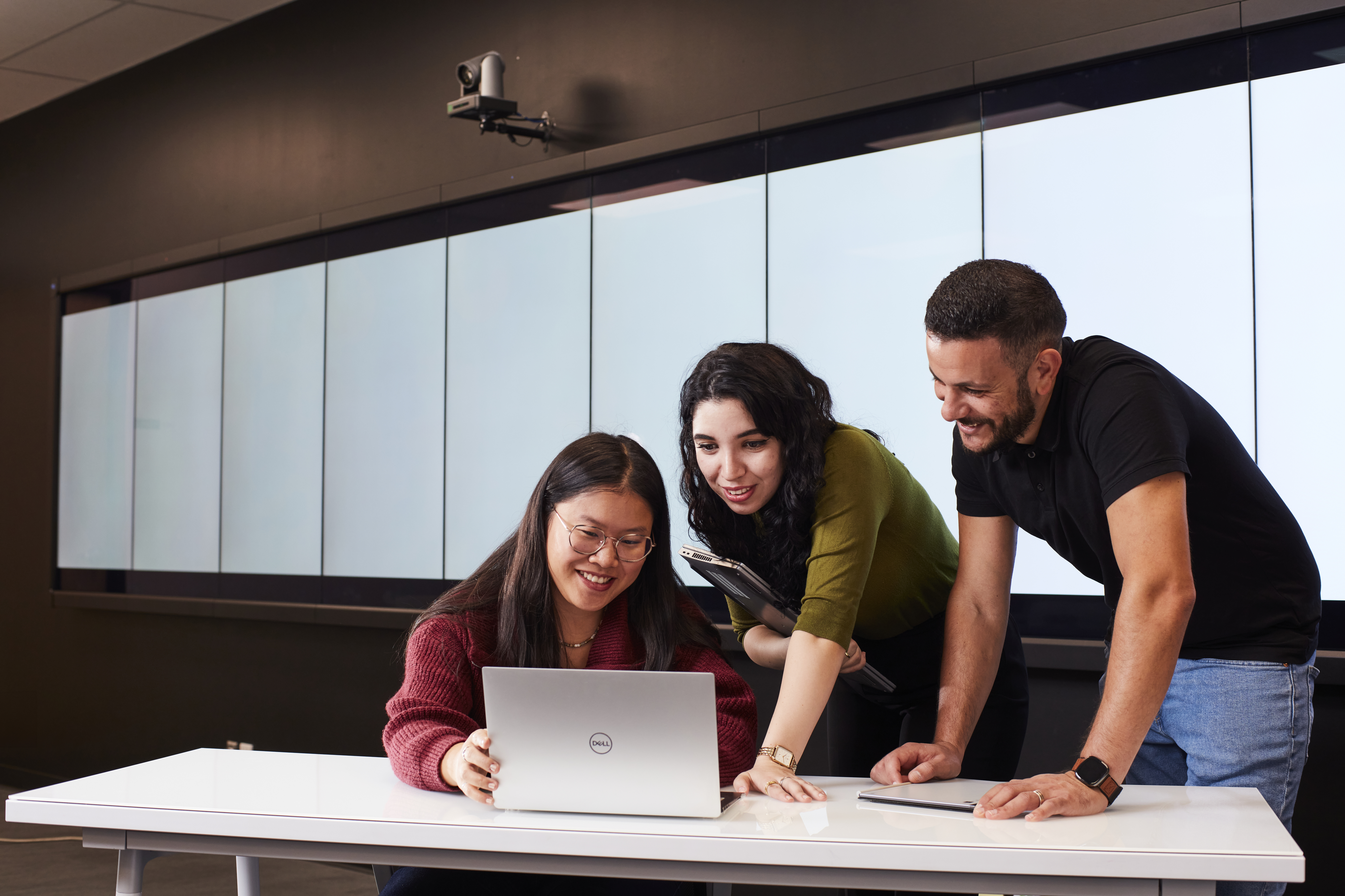 Un groupe d'étudiants collabore autour d'un ordinateur portable, partageant des idées dans un environnement moderne et dynamique.