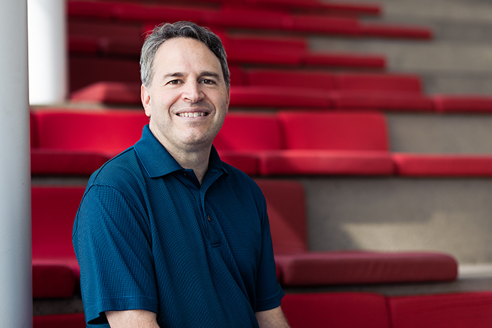 "Faculty member smiling in front of red auditorium seats at a tech university."
