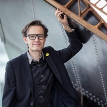 Un professeur en sciences appliquées posant avec confiance, illustrant l'innovation et l'engagement en technologie.