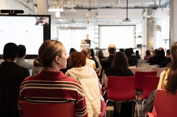 Un groupe d'étudiants assiste à une présentation dans un environnement moderne, favorisant l'échange d'idées et d'innovations.