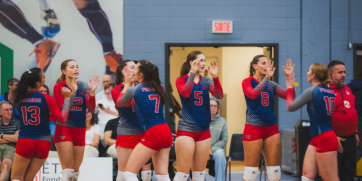Équipe de volleyball en action, célébrant un point avec enthousiasme lors d'un match compétitif, entourée de spectateurs.