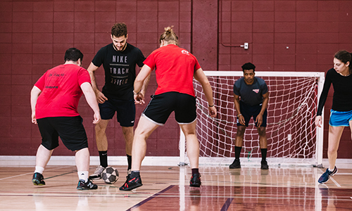 Étudiants universitaires jouant au football en salle lors d'un match amical.