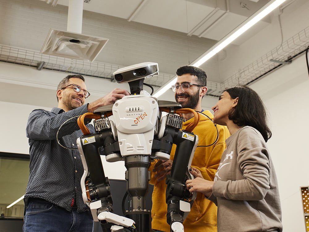 Des étudiants et un professeur collaborent autour d'un robot, explorant la technologie et l'innovation en robotique.