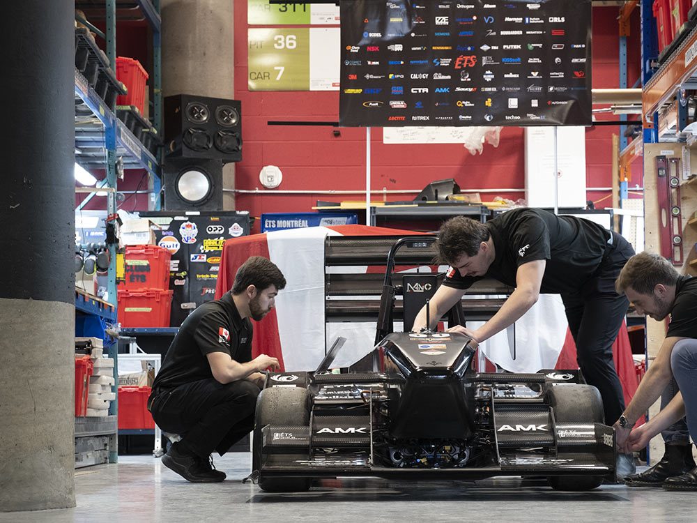 Des étudiants en ingénierie travaillent sur un prototype de voiture de compétition dans un atelier dynamique et moderne.