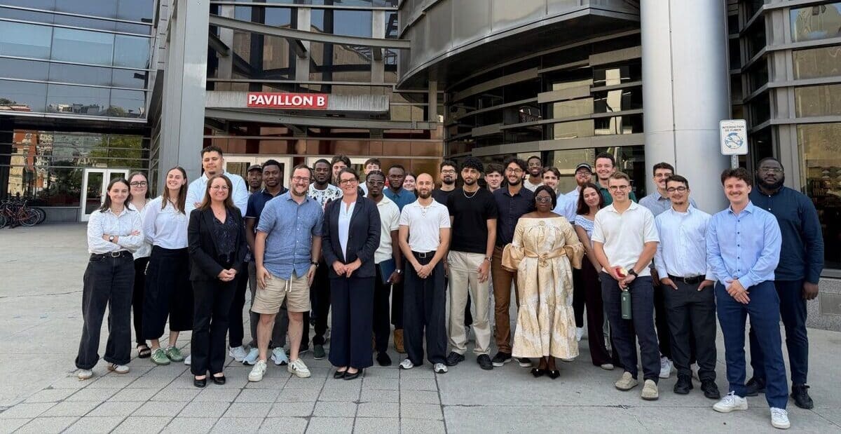 Groupe d'étudiants et d'enseignants devant le Pavillon B, symbolisant la diversité et l'engagement académique.