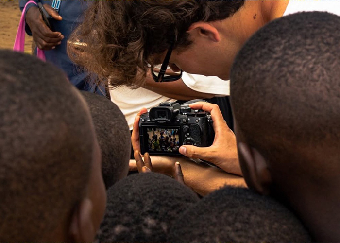 Un groupe de jeunes observe avec curiosité les photos sur un appareil photo, captivés par les moments partagés.