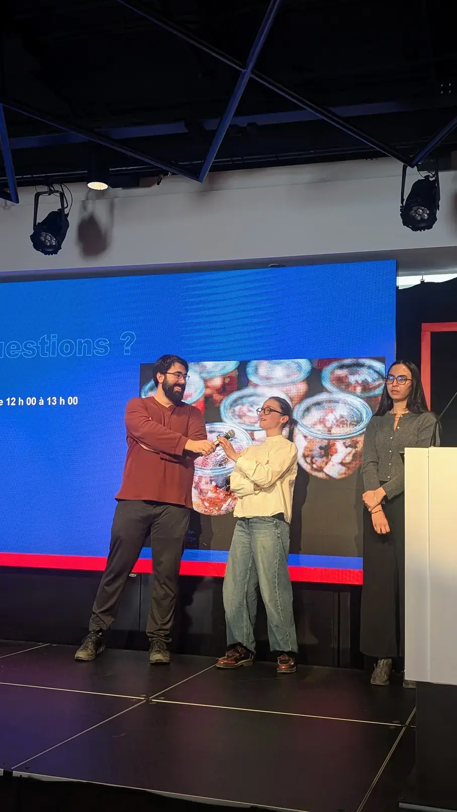 Félix Veillette, étudiant à la maitrise en génie de l'environnement, Alix Vignalou, étudiante à la maîtrise projet en génie de l’environnement, et Niama Yahiaoui, étudiante au doctorat en génie des systèmes, sur une scène, en train d'interagir.