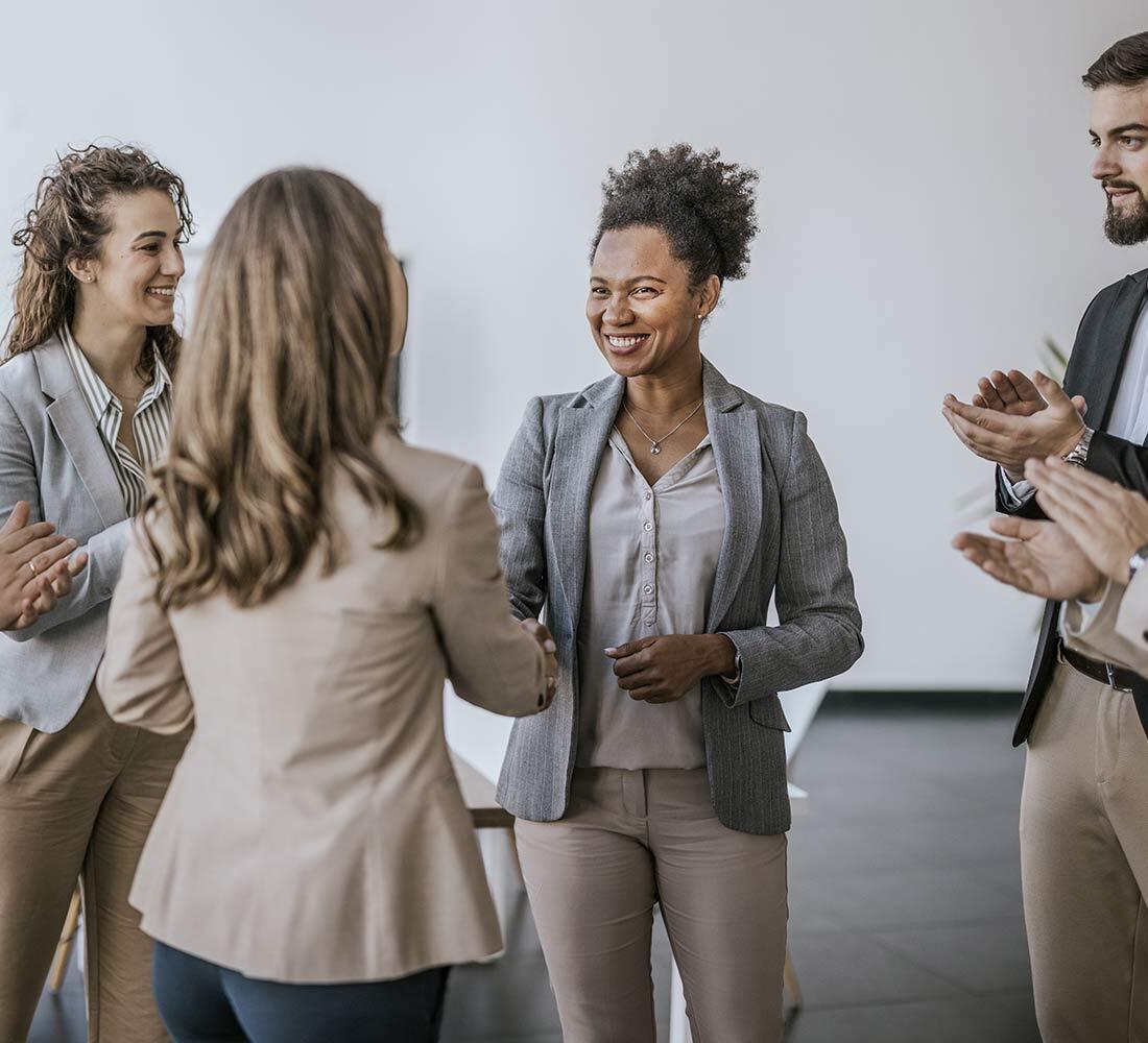 A professional meeting where individuals are warmly greeting and applauding a successful collaboration.
