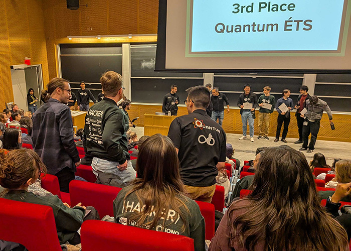 Étudiants en technologie discutent dans une salle de classe, devant un écran annonçant les résultats d'une compétition.