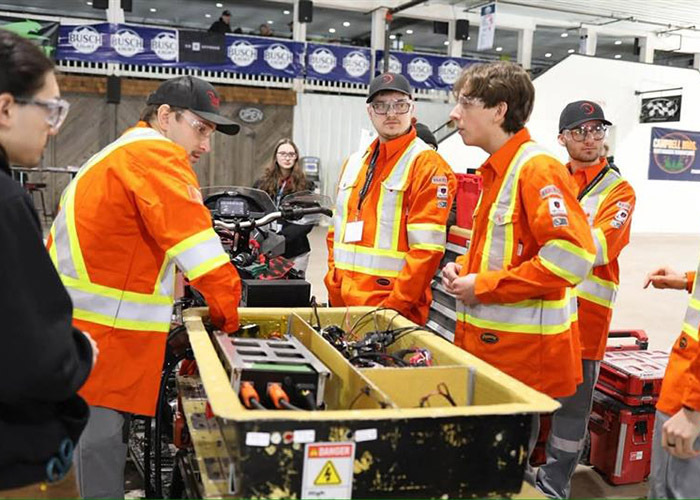 Étudiants en technologie collaborent autour d'un projet, échangeant des idées et analysant des équipements techniques sur le terrain.