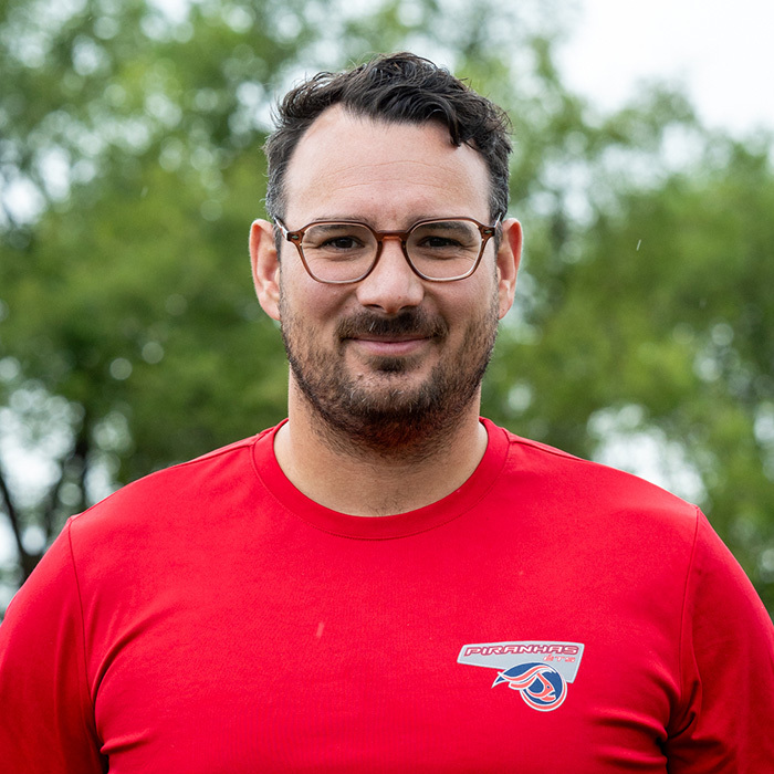 Coach de l'équipe Piranhas ETS souriant, portant un sweat à capuche sportif.
