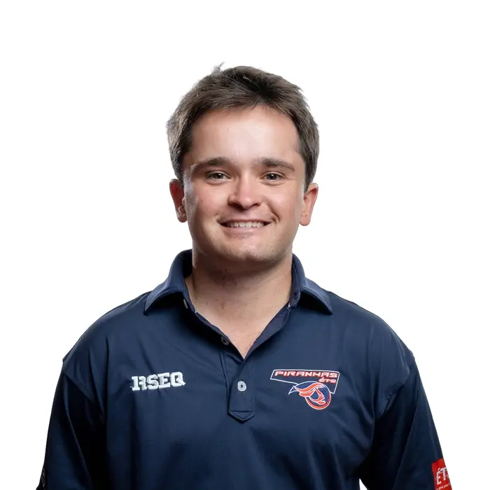 Étudiant souriant de l'Université en technologie supérieure, portant un polo de l'équipe des Piranhas, fait preuve d'enthousiasme et de camaraderie.