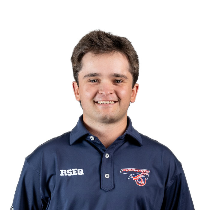 Étudiant souriant de l'Université en technologie supérieure, portant un polo de l'équipe des Piranhas, fait preuve d'enthousiasme et de camaraderie.