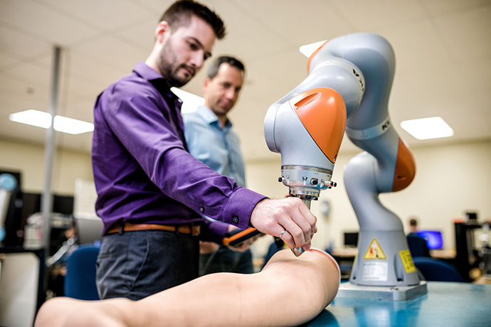 Étudiants en technologie testent un bras robotique pour applications médicales.