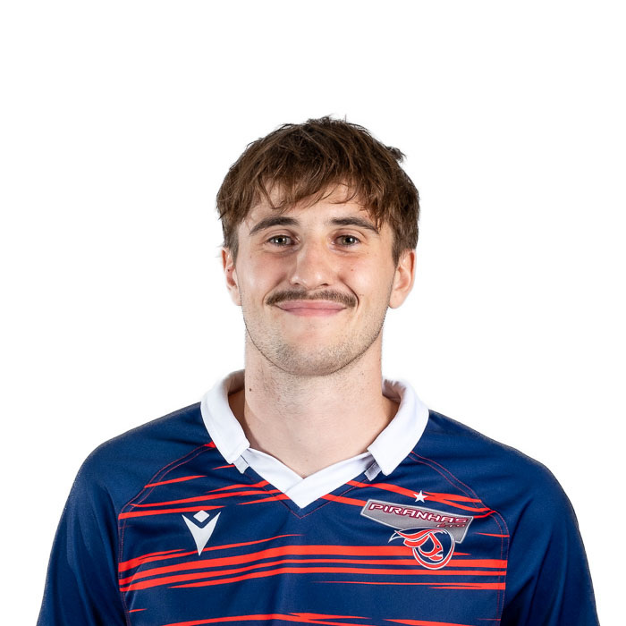 Un étudiant de l'Université en technologie supérieur sourit fièrement, vêtu d'un maillot aux couleurs vives de l'équipe.