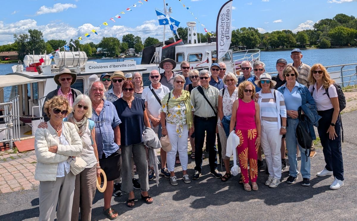 Groupe de personnes souriantes réunies près d'un bateau, prêtes à embarquer pour une croisière à travers la belle nature environnante.