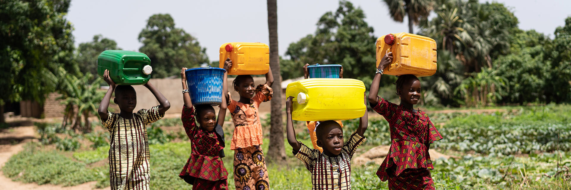 Jeunes portant de l'eau sur la tête, innovation et solidarité pour l'accès à l'eau.