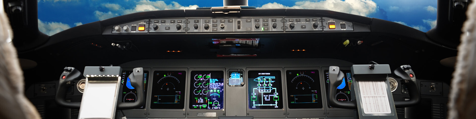 Tableau de bord d'avion avec écrans et commandes de pilotage.