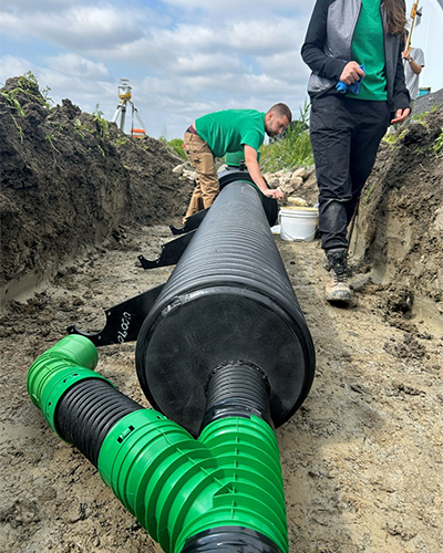 Des étudiants installent un système de drainage dans un chantier, montrant l'application pratique des techniques en génie civil.
