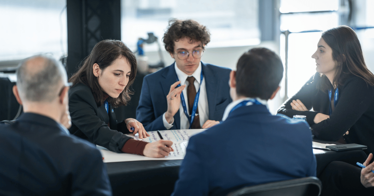 Un groupe de participants échangent des idées lors d'une séance de travail collaborative, illustrant l'esprit d'innovation et de coopération.