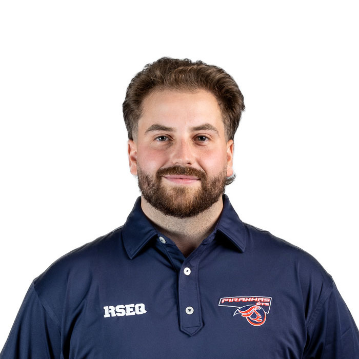 Un jeune homme souriant porte un polo de l'université, affichant l'emblème des Piranhas et un logo. Ambiance professionnelle et amicale.
