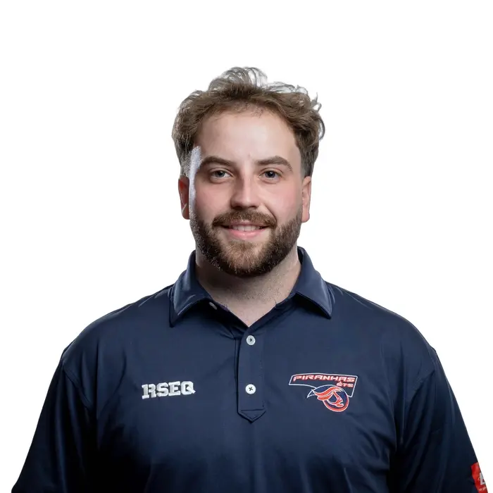 Un jeune homme souriant porte un polo de l'université, affichant l'emblème des Piranhas et un logo. Ambiance professionnelle et amicale.