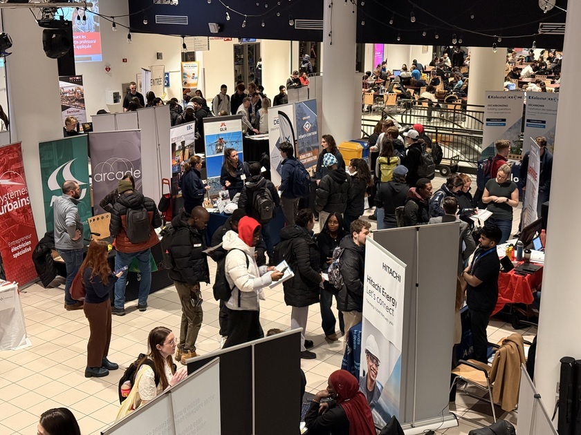 Des étudiants discutent avec des recruteurs lors d'un événement de réseautage, entourés de stands d'entreprises et d'informations.
