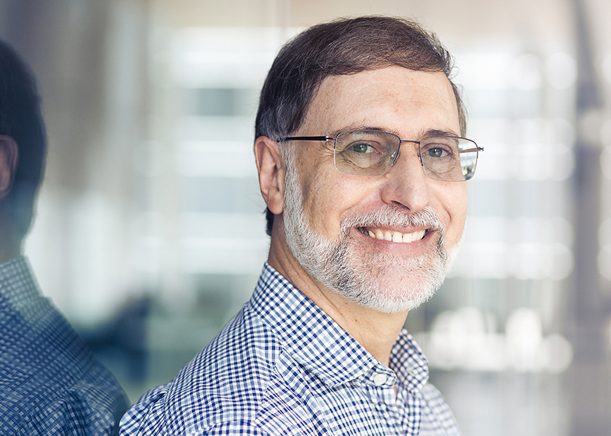 Smiling professional in glasses and checkered shirt at a tech university.